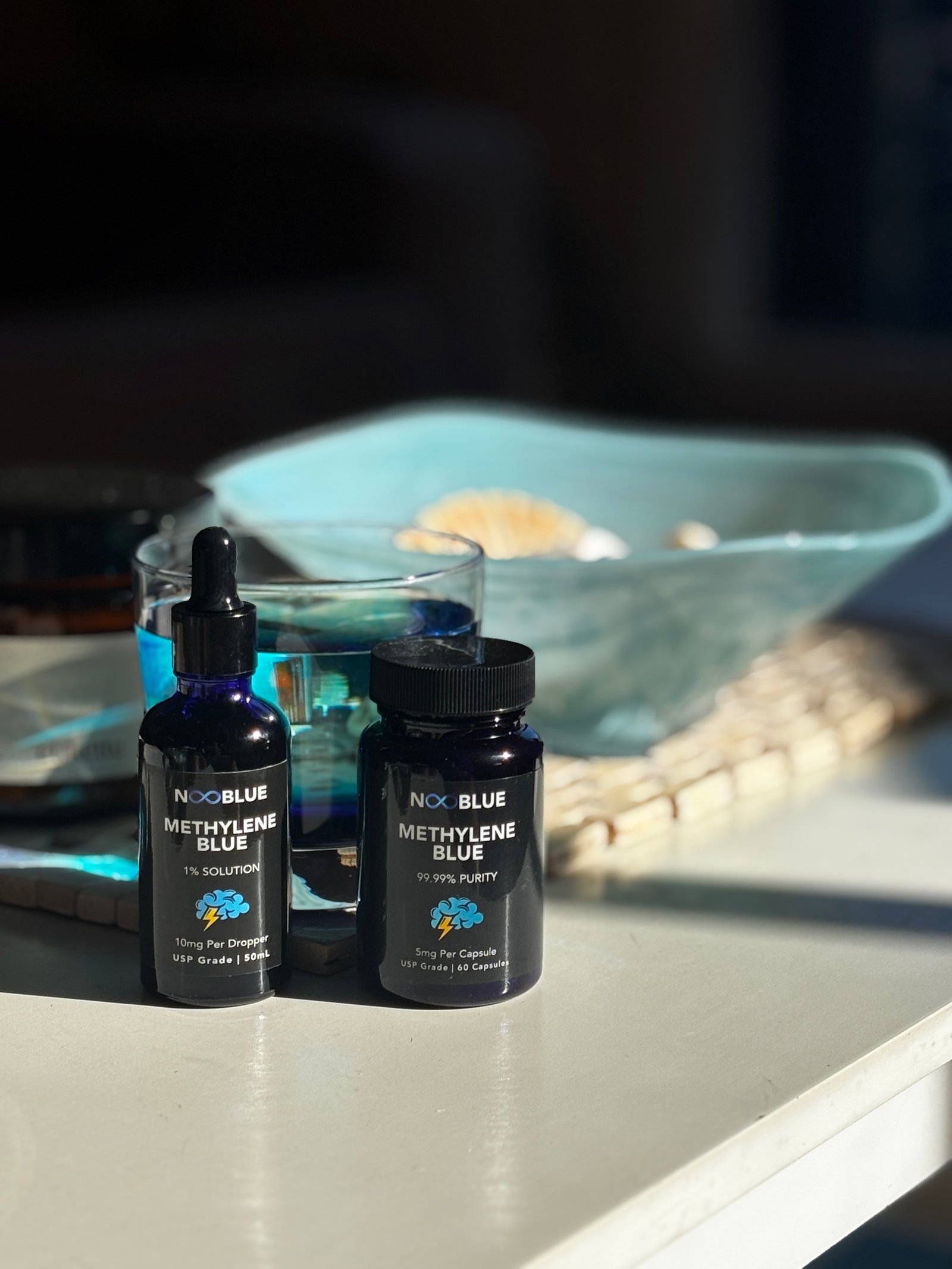 NooBlue Methylene Blue capsules and liquid solution bottles in natural sunlight