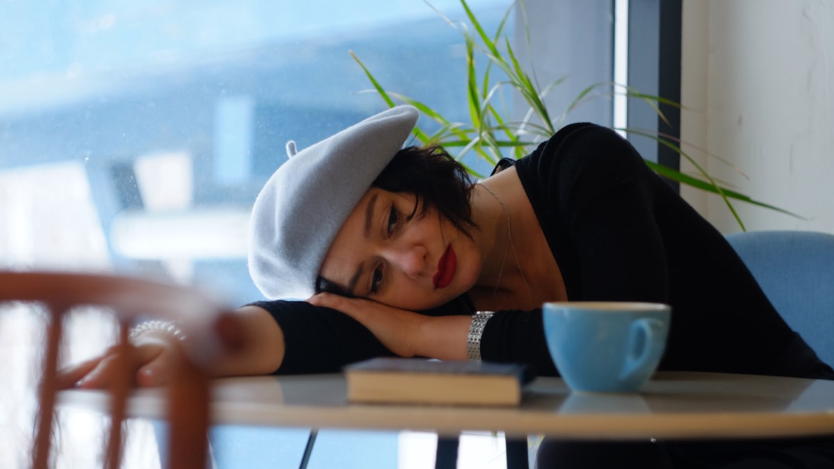 Woman resting her head on a desk, illustrating covid brain fog and post-viral mental fatigue
