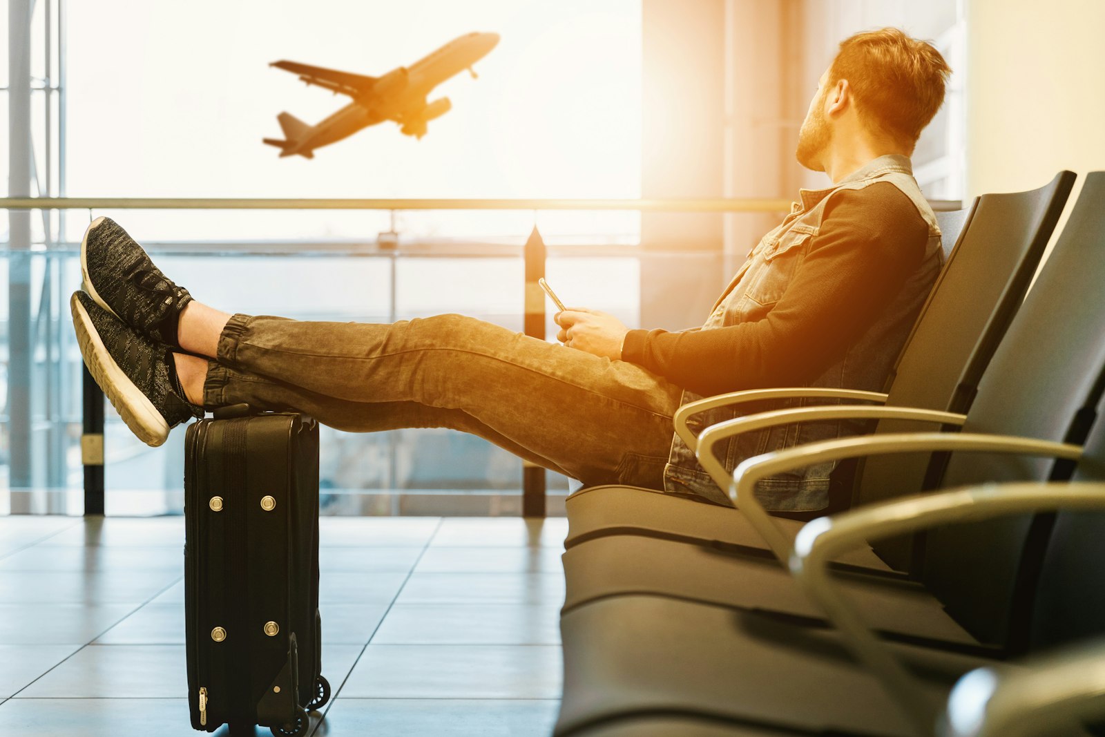 Best supplements for travel fatigue guide: a traveler resting with feet on luggage at an airport window
