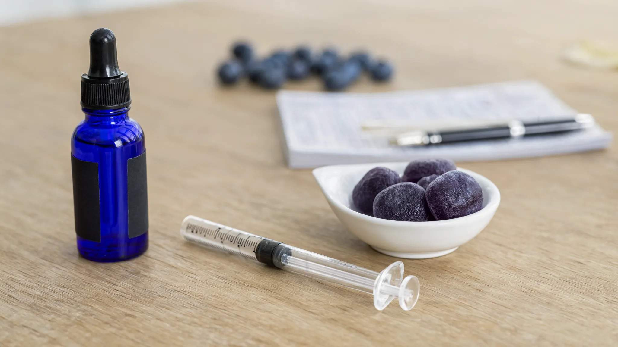 Biotech Labs methylene blue review: a cobalt dropper bottle, an oral measuring syringe and purple methylene blue gummies on a desk