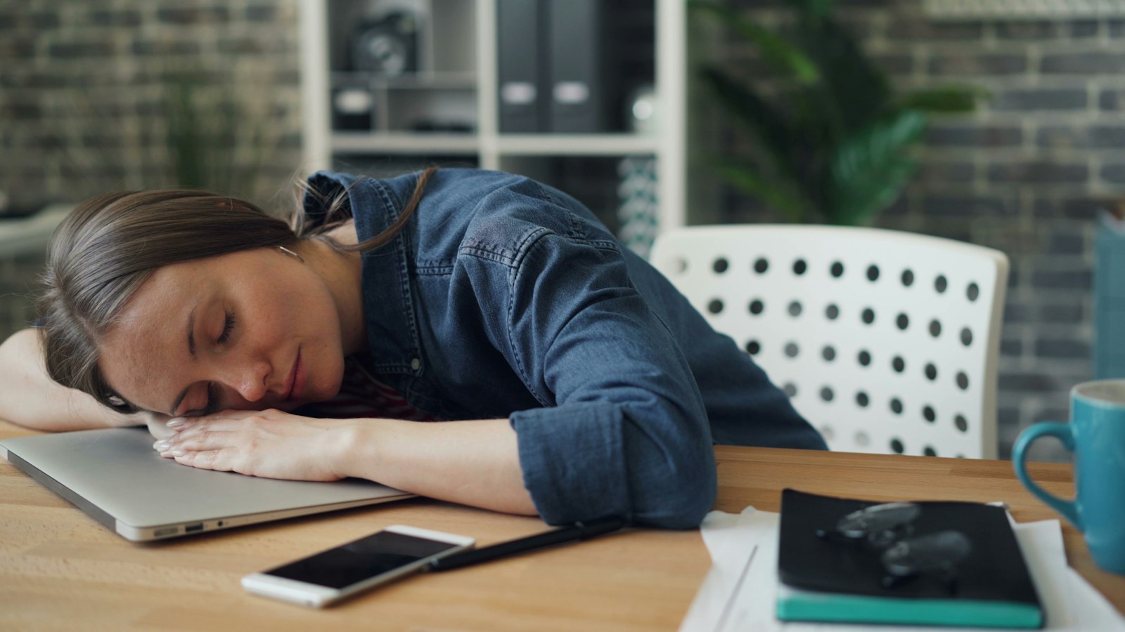 Woman resting her head on a laptop, wondering how to get rid of brain fog