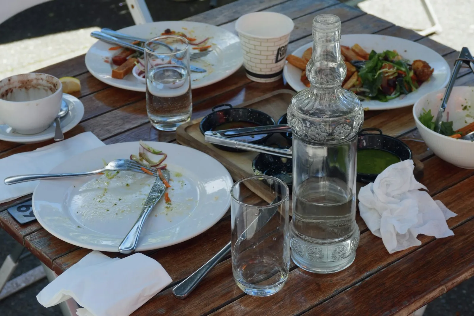 Empty lunch plates and water glasses on a table, a common moment to ask why do I get so tired after I eat